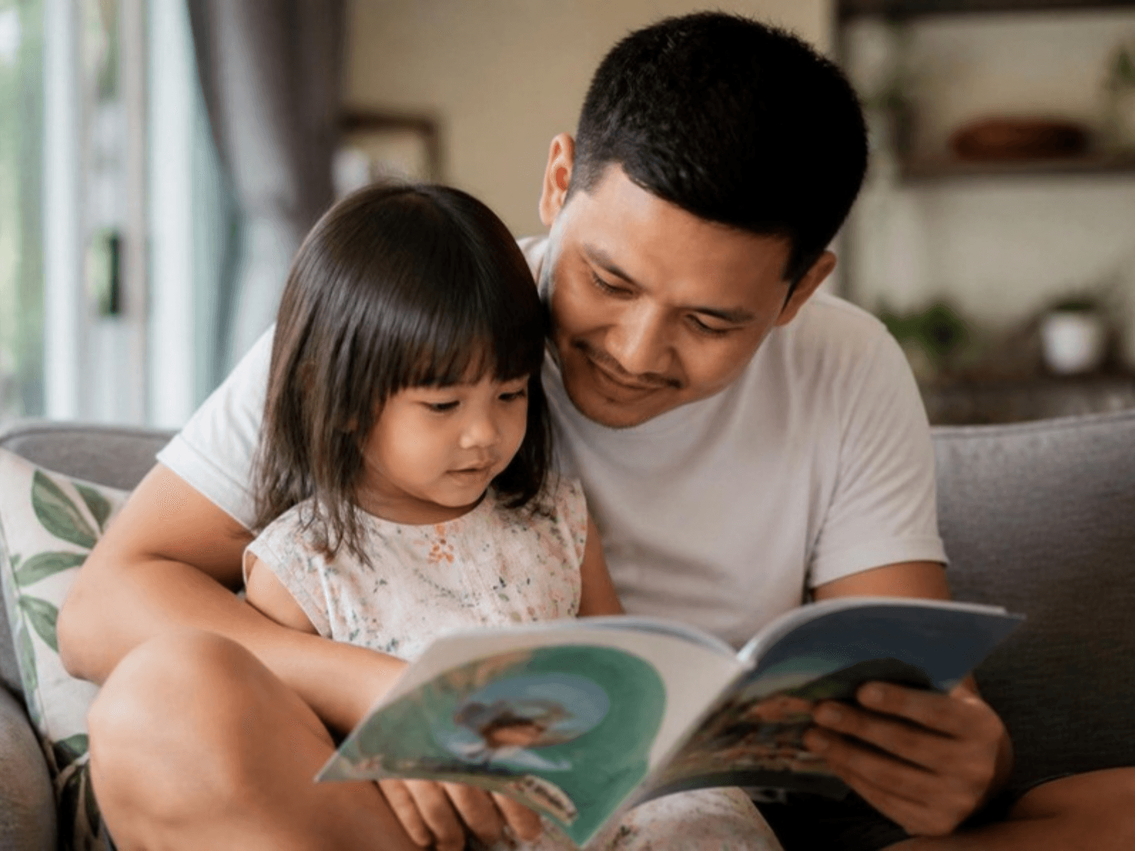 A father reading with his daughter at home